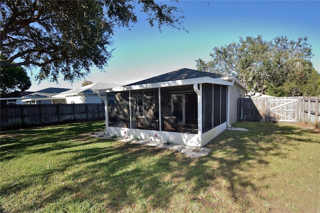 rear view of house with a yard and a sunroom