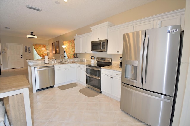 kitchen with white cabinetry, appliances with stainless steel finishes, sink, and kitchen peninsula