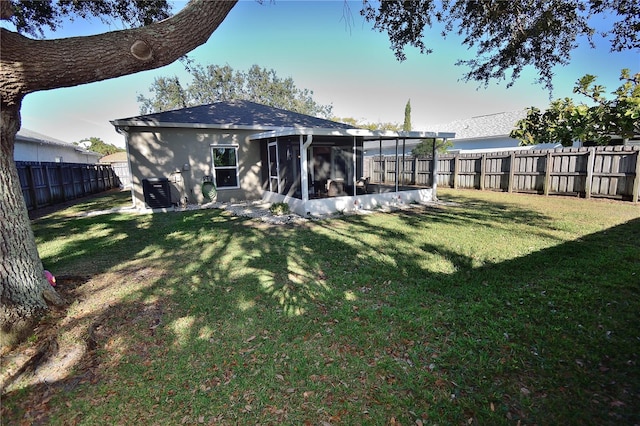 rear view of property with a yard, central AC unit, and a sunroom