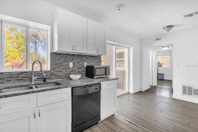 kitchen with white cabinetry, black dishwasher, sink, decorative backsplash, and dark stone counters