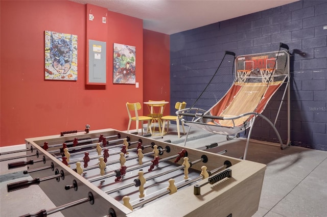 recreation room featuring electric panel and concrete floors