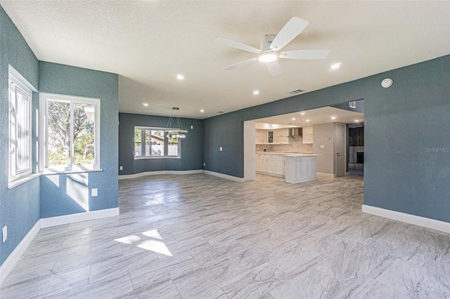 unfurnished living room featuring baseboards, visible vents, and ceiling fan