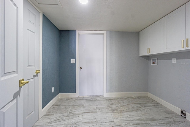 clothes washing area with marble finish floor, a textured wall, baseboards, hookup for a washing machine, and cabinet space