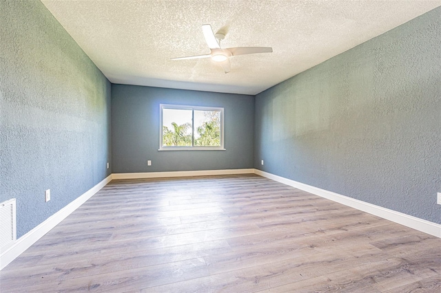 spare room with a ceiling fan, a textured wall, and wood finished floors