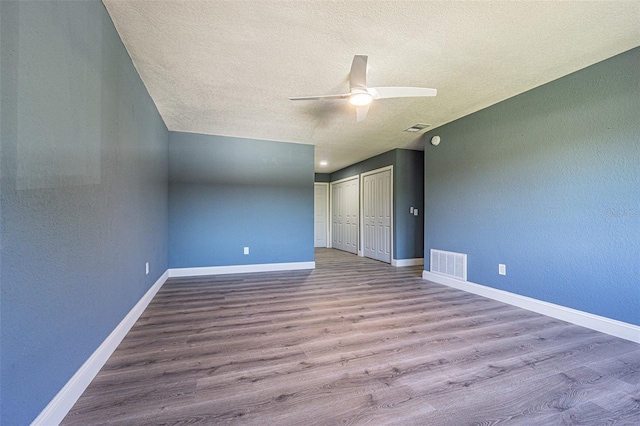 unfurnished bedroom with baseboards, a textured ceiling, wood finished floors, and visible vents