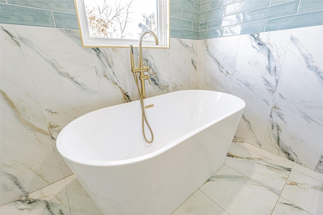 full bath featuring a soaking tub and marble finish floor