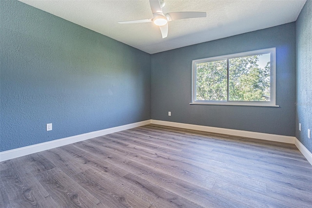 empty room with a ceiling fan, a textured wall, and wood finished floors