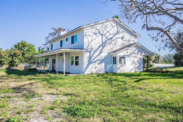 back of house featuring a lawn, a chimney, and stucco siding
