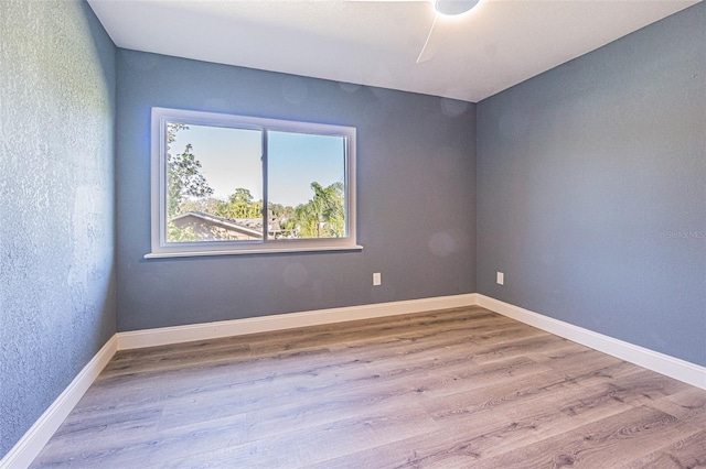 empty room with baseboards, a textured wall, and wood finished floors
