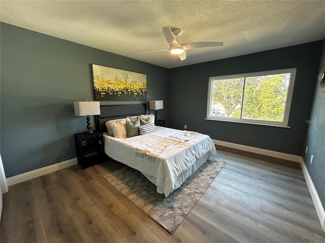 bedroom featuring baseboards, a ceiling fan, a textured ceiling, and wood finished floors