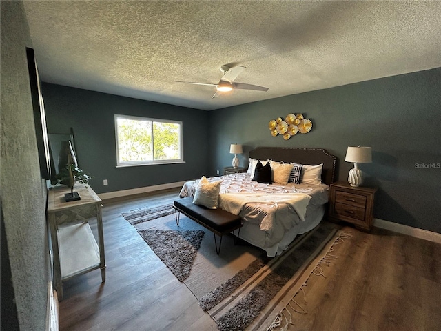 bedroom featuring baseboards, a textured ceiling, and wood finished floors