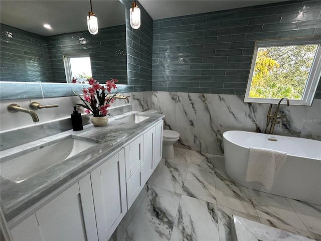 bathroom with a freestanding tub, tile walls, a sink, and marble finish floor
