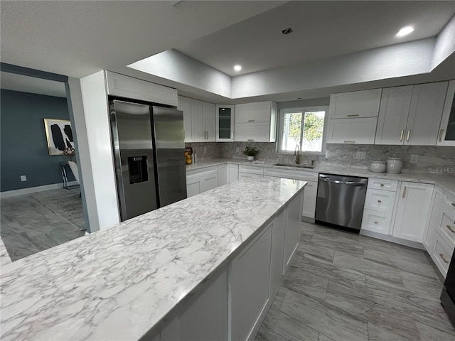 kitchen featuring backsplash, appliances with stainless steel finishes, a sink, and marble finish floor