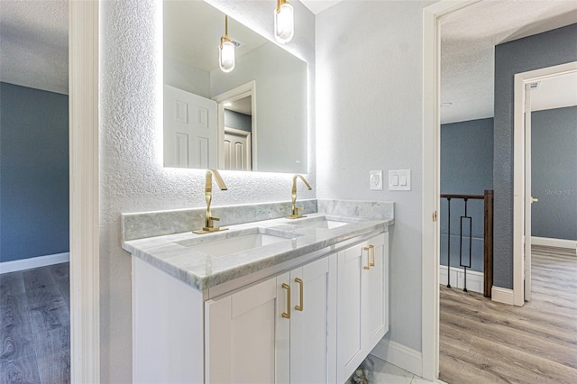 full bath featuring baseboards, a sink, a textured ceiling, and wood finished floors