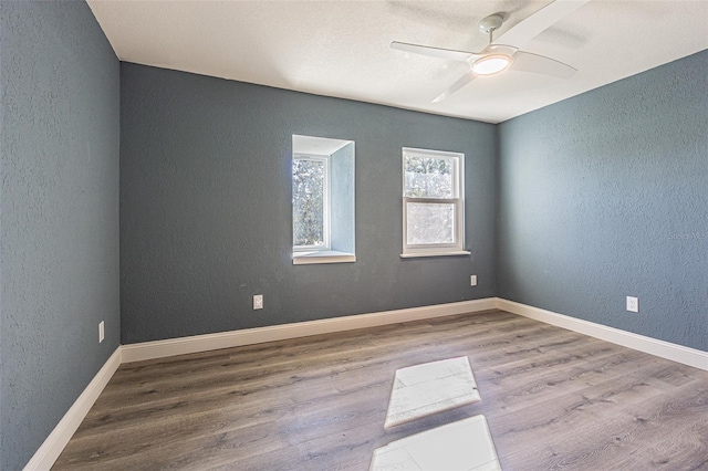 unfurnished room featuring baseboards, a textured wall, ceiling fan, and wood finished floors