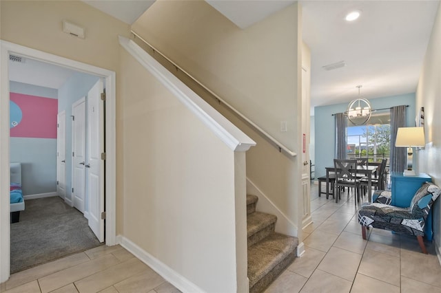 stairs with tile patterned flooring and an inviting chandelier