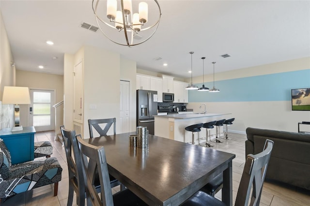 dining room with sink, light tile patterned floors, and a chandelier