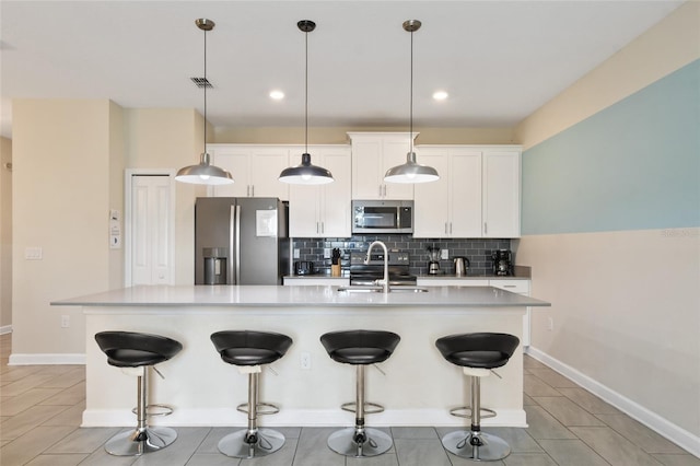 kitchen with a kitchen island with sink, hanging light fixtures, white cabinets, and stainless steel appliances