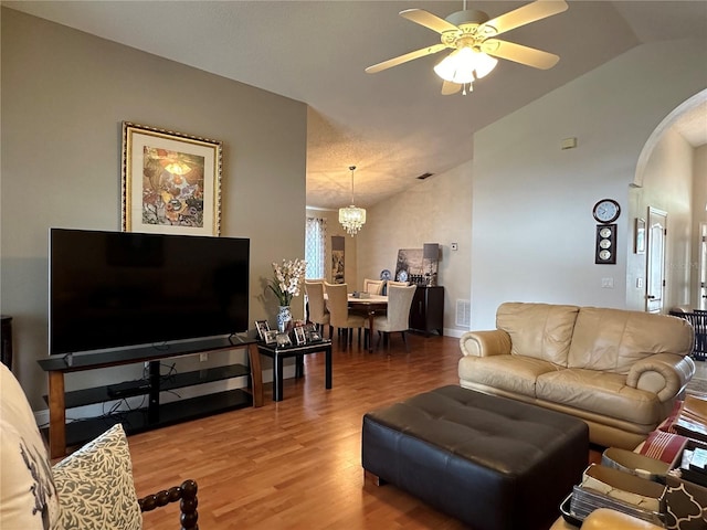 living room with hardwood / wood-style flooring, ceiling fan with notable chandelier, a healthy amount of sunlight, and lofted ceiling