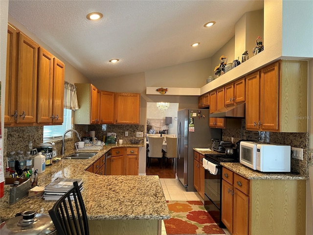 kitchen featuring kitchen peninsula, appliances with stainless steel finishes, vaulted ceiling, sink, and light tile patterned floors