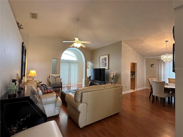 living room featuring ceiling fan with notable chandelier, dark hardwood / wood-style flooring, lofted ceiling, and a textured ceiling