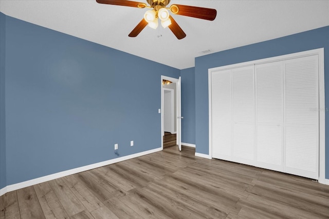 unfurnished bedroom featuring hardwood / wood-style floors, a closet, and ceiling fan