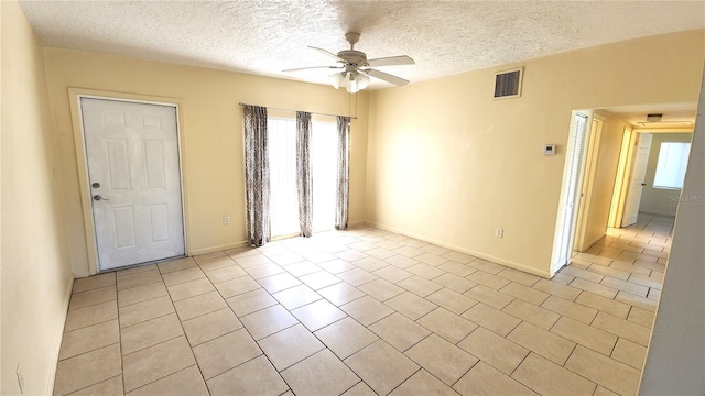 empty room featuring light tile patterned floors, a textured ceiling, and ceiling fan