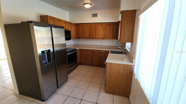 kitchen featuring black appliances, light tile patterned floors, sink, and a wealth of natural light