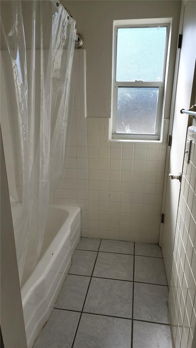 bathroom featuring tile patterned floors, shower / tub combo, and tile walls