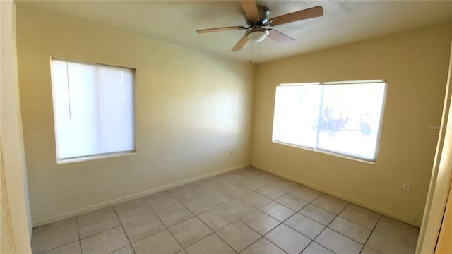 tiled empty room with ceiling fan and plenty of natural light