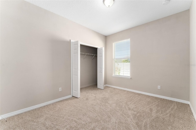 unfurnished bedroom with light carpet and a closet