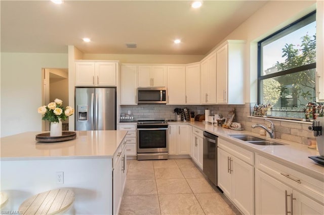 kitchen with a kitchen island, sink, white cabinets, decorative backsplash, and stainless steel appliances