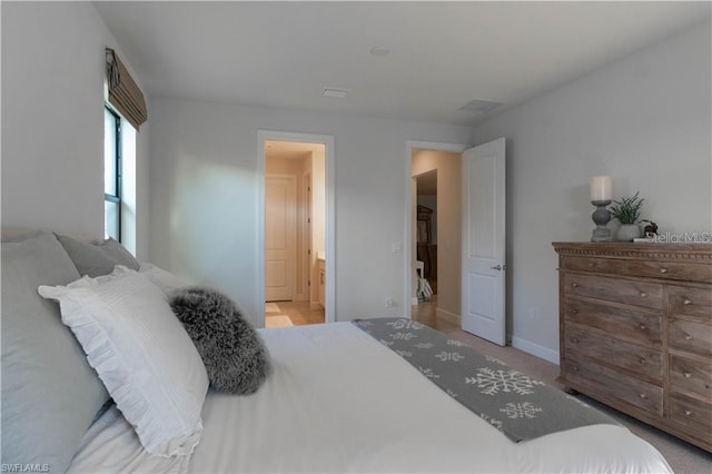 bedroom featuring ensuite bath and light colored carpet