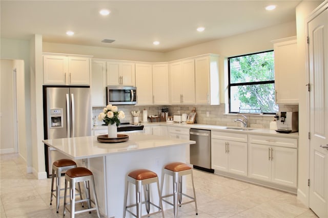 kitchen with a kitchen island, white cabinetry, appliances with stainless steel finishes, and sink