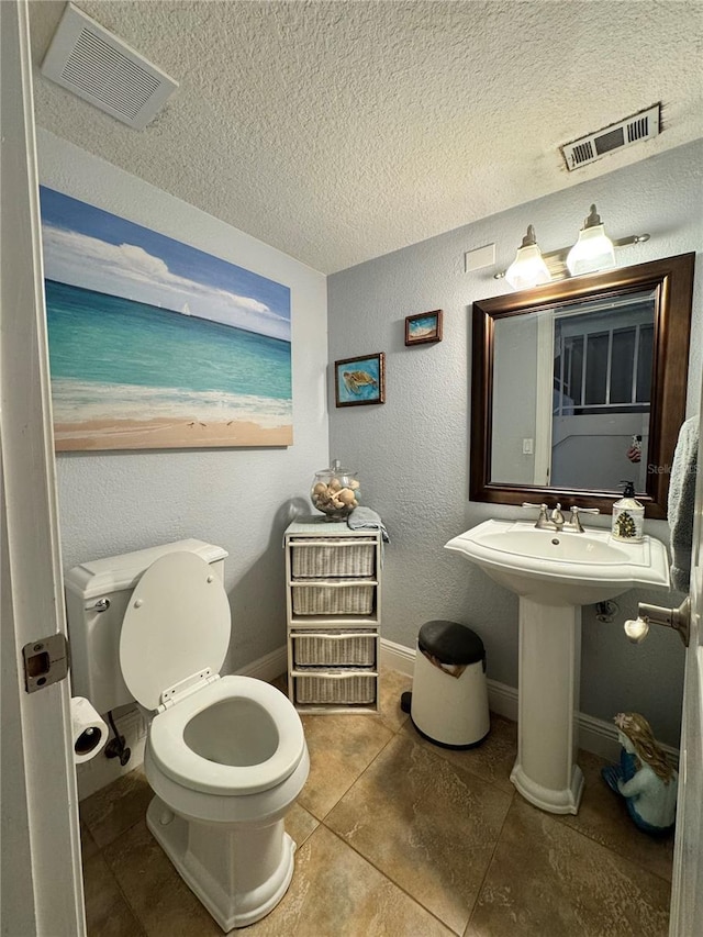 bathroom featuring toilet, a textured ceiling, and tile patterned floors