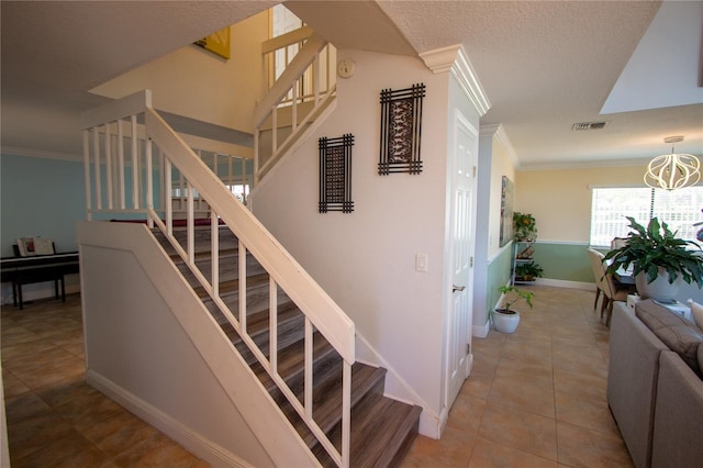 stairway with tile patterned flooring, a textured ceiling, and crown molding