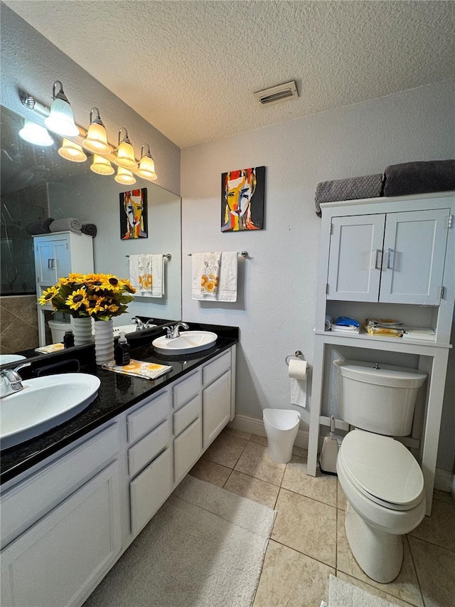 bathroom featuring tile patterned floors, vanity, toilet, and a textured ceiling