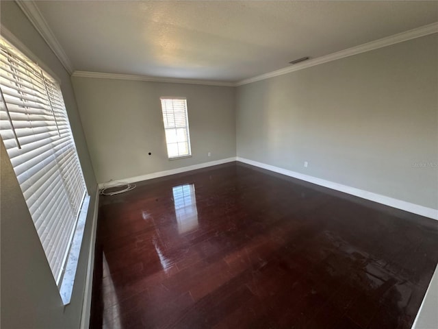 unfurnished room with ornamental molding, dark wood-type flooring, visible vents, and baseboards