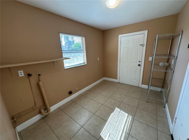 clothes washing area with washer hookup, laundry area, baseboards, and light tile patterned floors