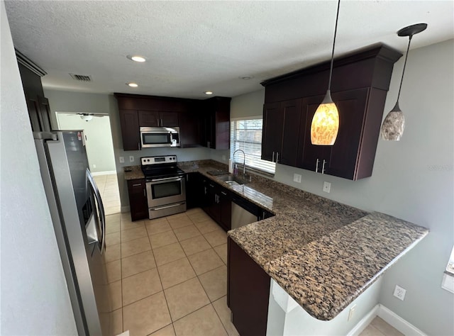 kitchen with sink, kitchen peninsula, pendant lighting, light tile patterned floors, and appliances with stainless steel finishes