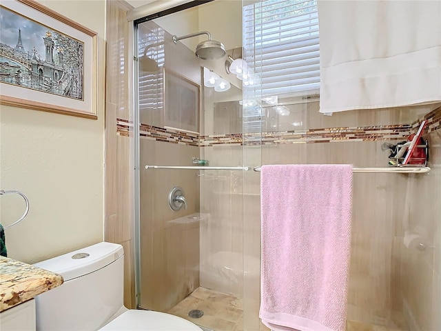 bathroom with a shower with door and toilet