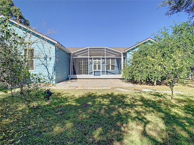 rear view of property featuring a patio, glass enclosure, and a lawn