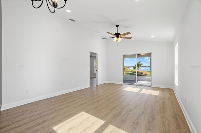 unfurnished living room featuring ceiling fan with notable chandelier, light hardwood / wood-style floors, and lofted ceiling