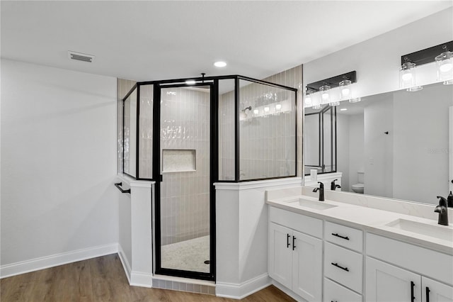 bathroom featuring a shower with shower door, toilet, wood-type flooring, and vanity