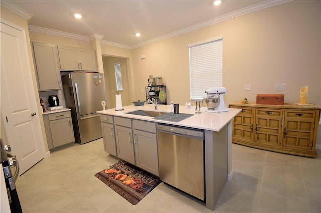 kitchen featuring gray cabinetry, sink, stainless steel appliances, crown molding, and a kitchen island with sink