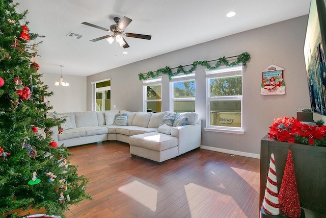 living room with ceiling fan with notable chandelier and dark wood-type flooring