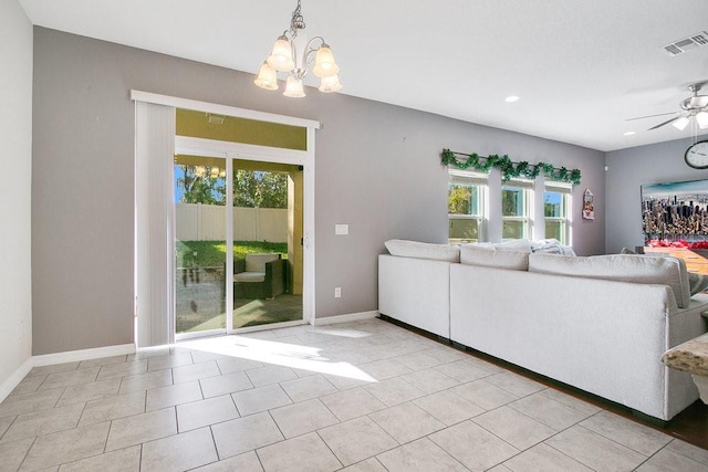 unfurnished living room with ceiling fan with notable chandelier, light tile patterned floors, and a wealth of natural light