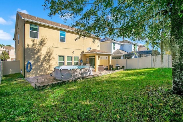 rear view of property with a lawn, a patio area, and a fenced in pool