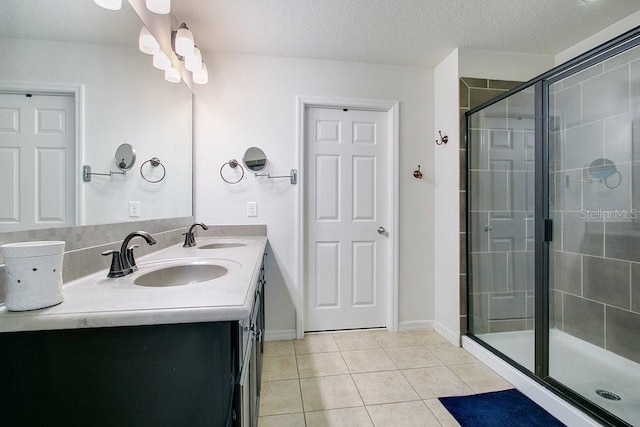 bathroom featuring tile patterned floors, a shower with door, vanity, and a textured ceiling