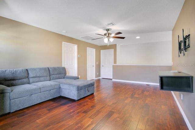 living room with ceiling fan, dark wood-type flooring, and a textured ceiling